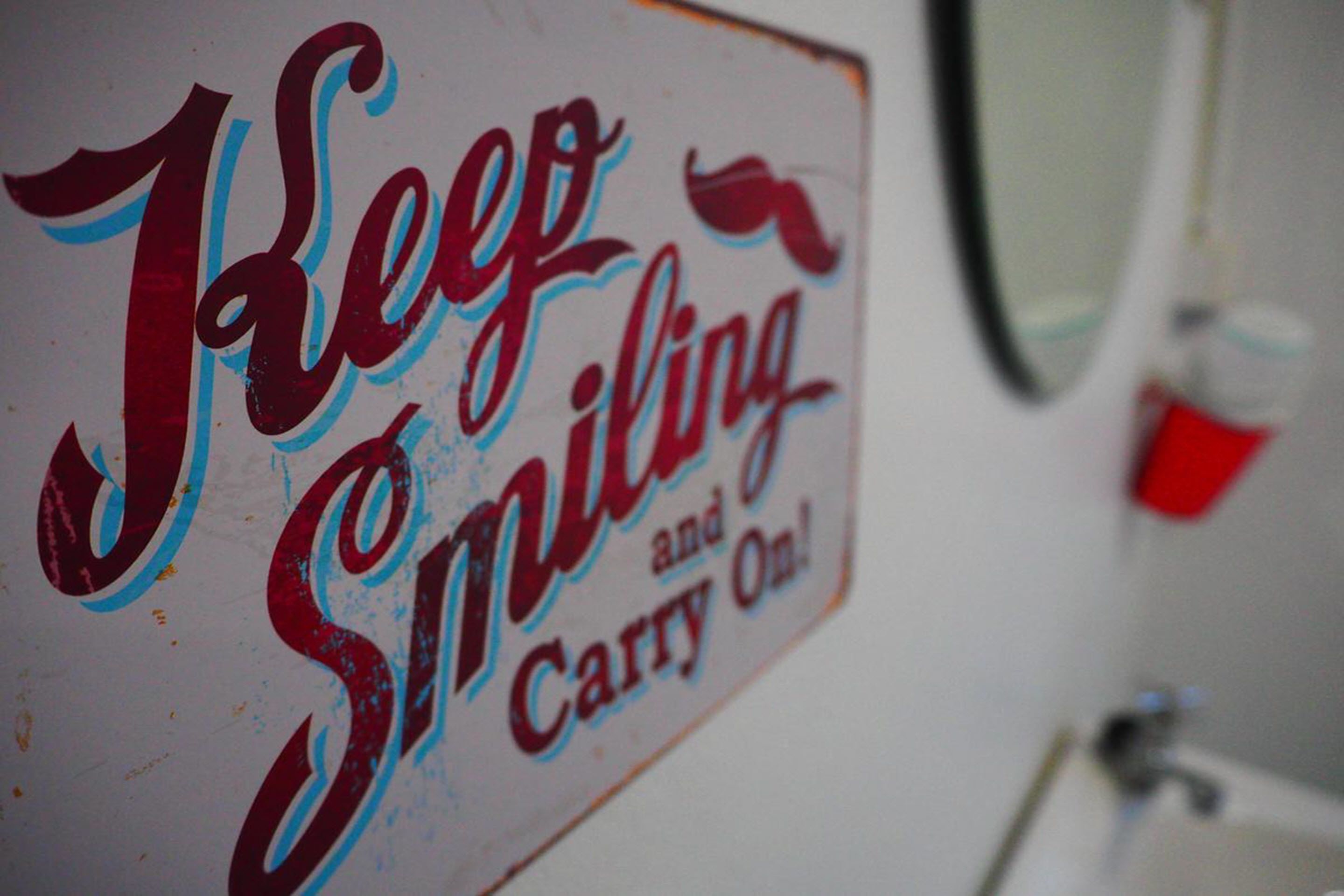 A sign with the text "Keep Smiling and Carry On!"