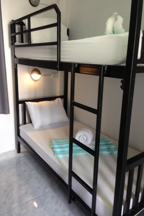 A bunk bed with a headboard, a bedside lamp, and a small shelf with toiletries.