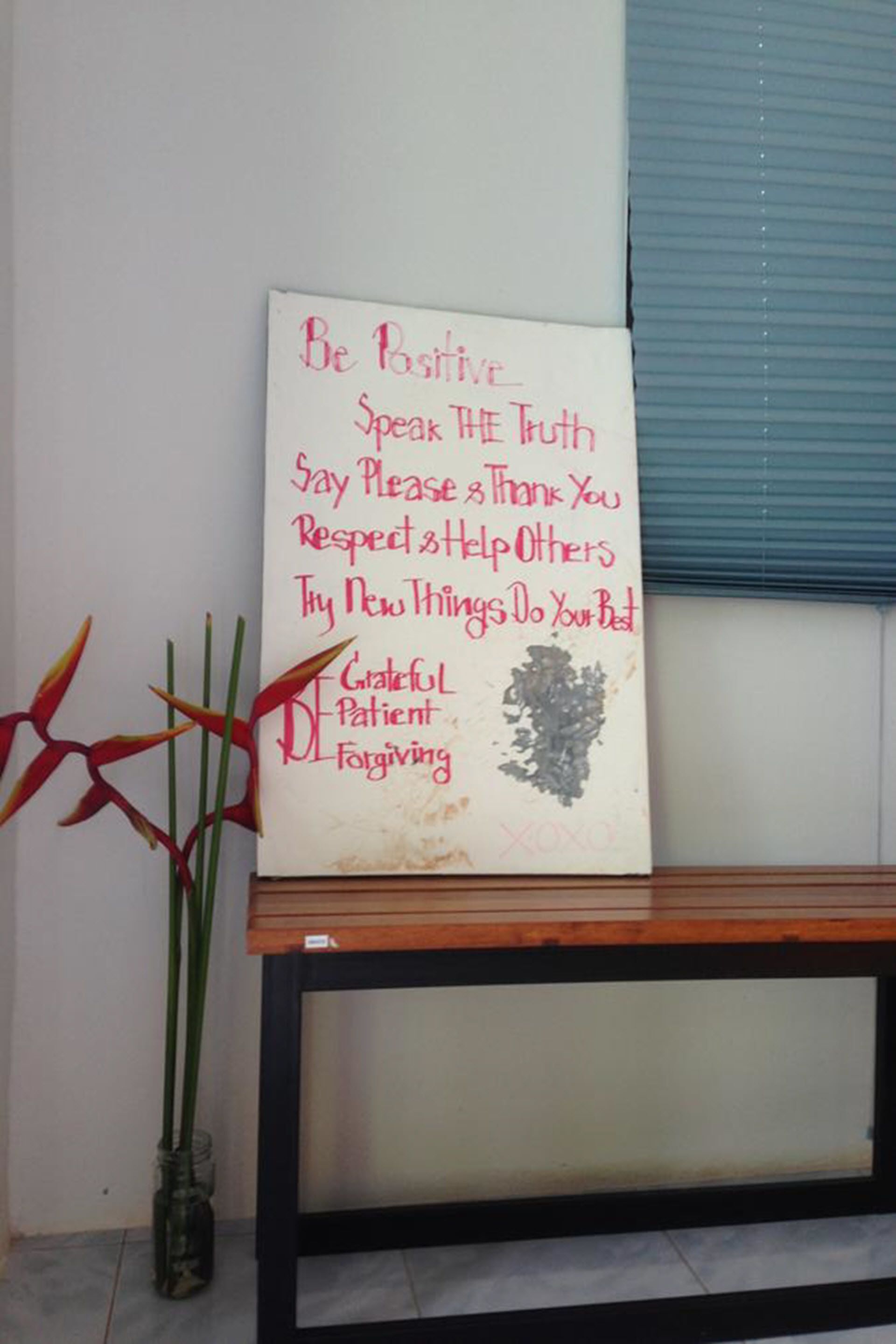Un letrero motivacional con una lista de afirmaciones positivas en una pared, ubicado sobre un banco de madera con superficie de vidrio.