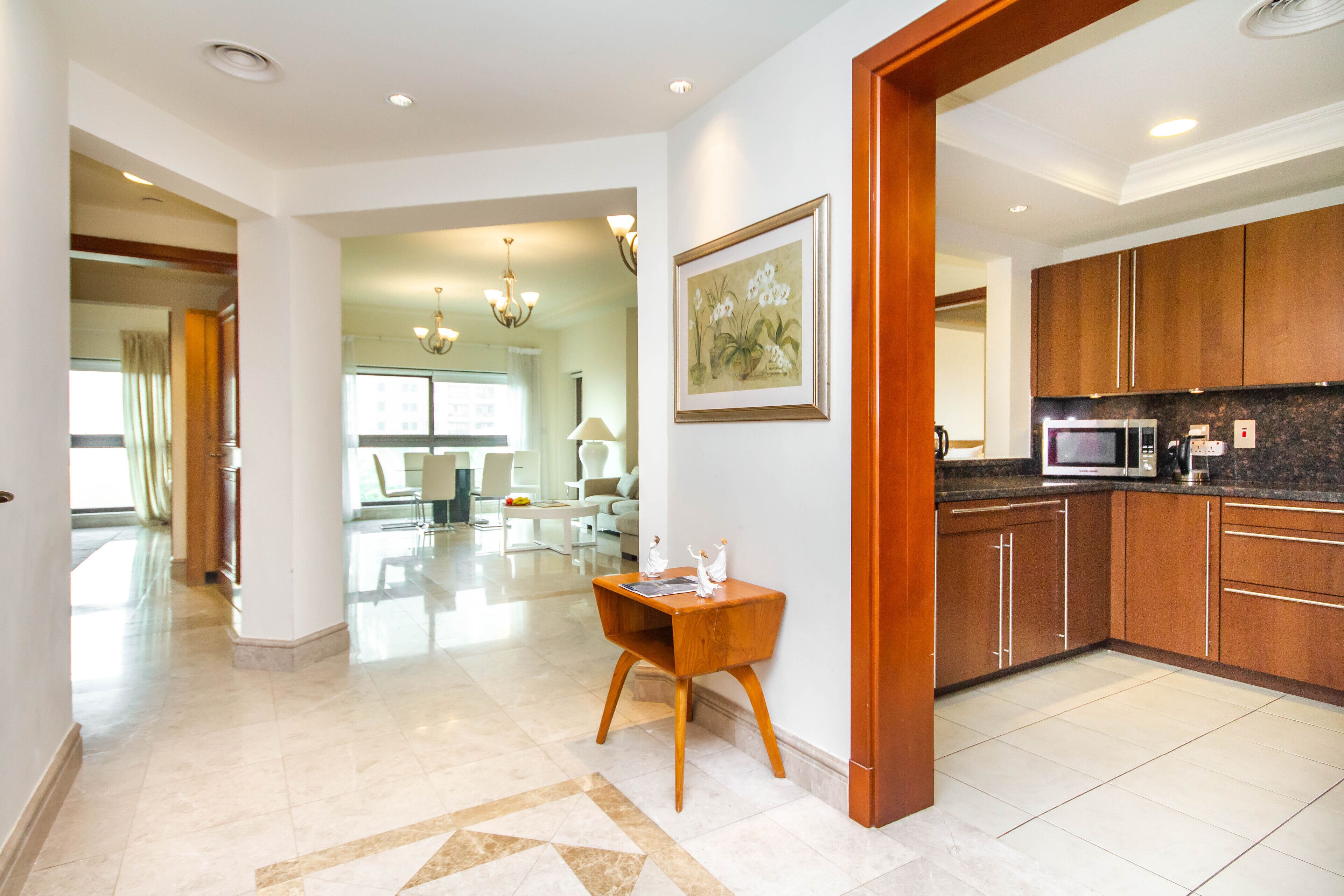 A spacious kitchen with wooden cabinets, a marble countertop, and a dining area with a table and chairs.