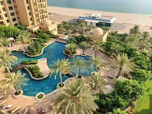 A resort with a central swimming pool surrounded by palm trees and lounge areas. - Bespoke Residences - South Residence (Dubai)
