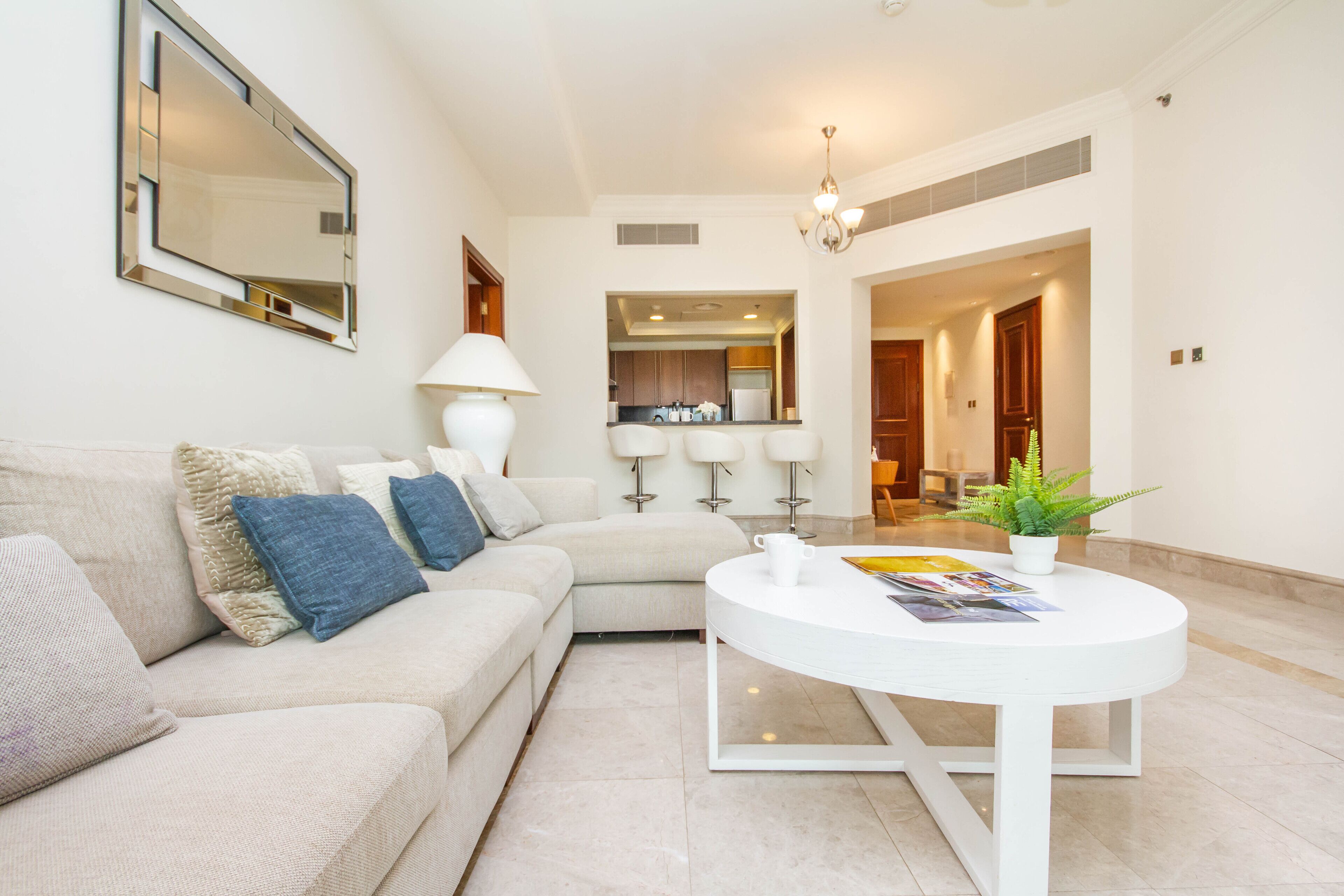 A modern living room with a sofa, a coffee table, and a kitchen in the background.