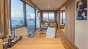 A modern hotel room with a large balcony, a seating area with a table and chairs, and a view of the ocean. - Lamaraz Arts Hotel (Algiers)
