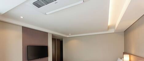 Habitación de hotel con dos camas, televisión, escritorio con lámpara y un pequeño rincón de descanso.