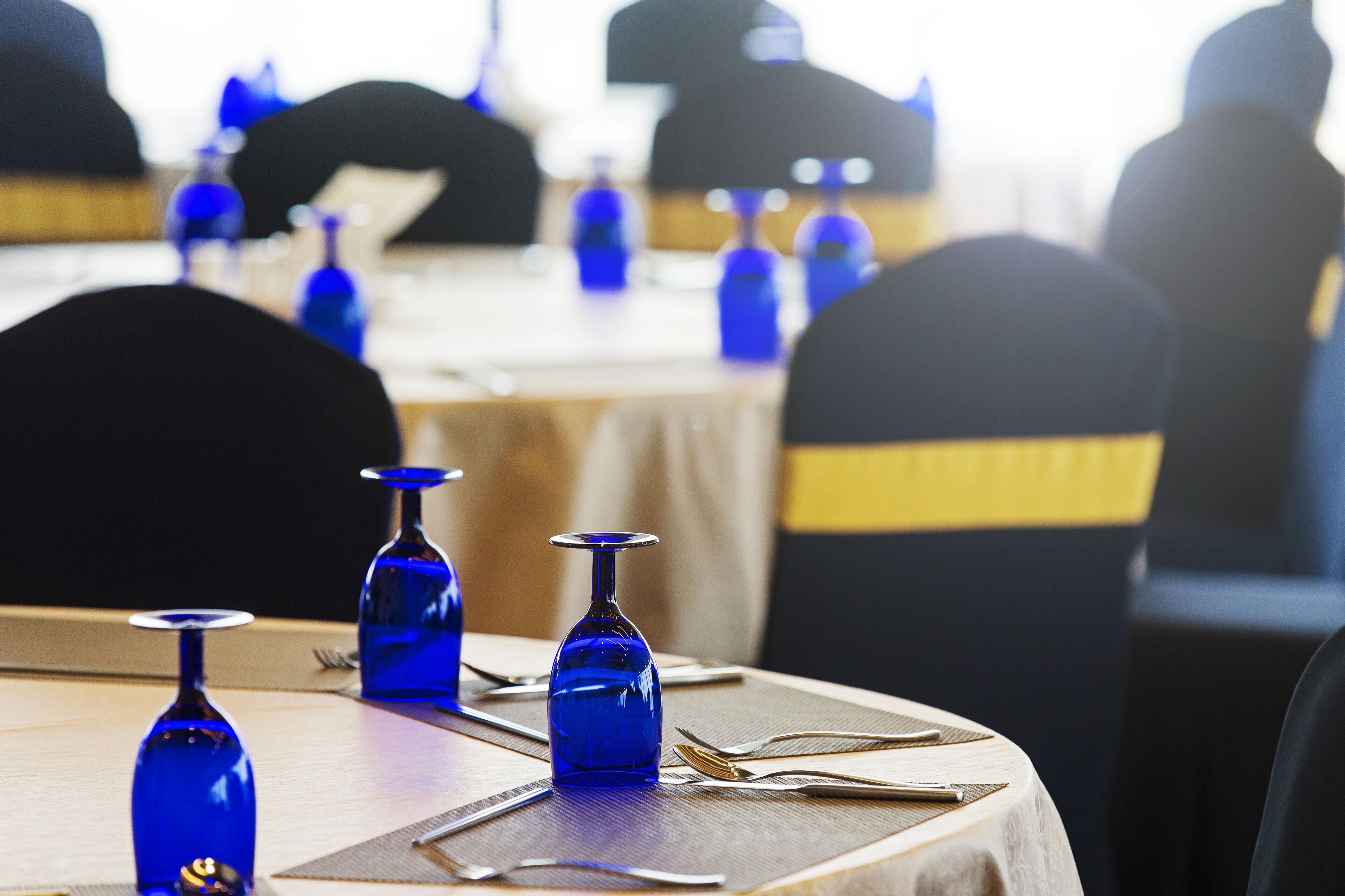 Un tavolo da pranzo con bicchieri di vetro blu e una sedia gialla.