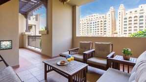 A balcony with a city view, a table with breakfast, and a sofa. - Bespoke Residences - North Residence (Dubai)