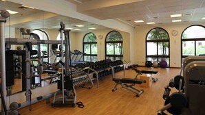 A spacious gym with various exercise equipment, large windows, and a mirrored wall. - Bespoke Residences - North Residence (Dubai)