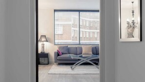 A modern living room with a grey sofa, a glass coffee table, a lamp, and a framed picture on the wall. - Incredible, Modern Apartment in South Kensington (London)