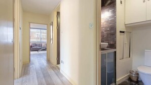 A hallway with a view to a living area, a tiled bathroom, and a small kitchen area. - Incredible, Modern Apartment in South Kensington (London)