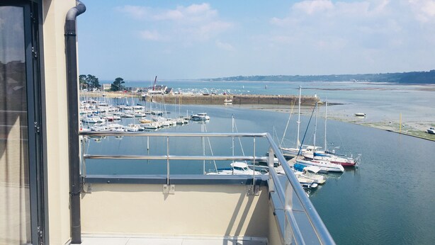 A balcony with a view of a marina filled with boats, a sandy beach, and a distant shoreline. - Le Nautica by Akena Hotels (Perros-Guirec)