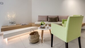 A modern living room with a sofa, a green armchair, a coffee table, and decorative items. - Le Nautica by Akena Hotels (Perros-Guirec)