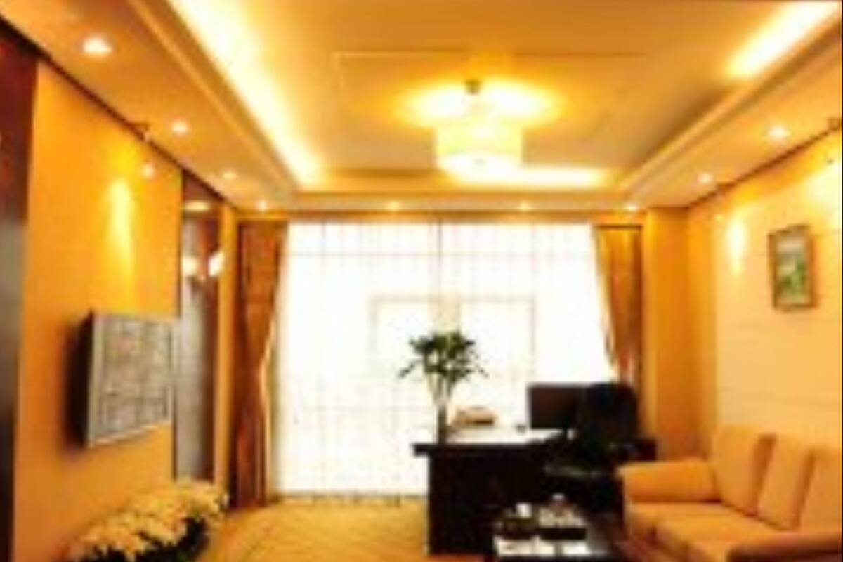 A hotel room with a sofa, a coffee table, a TV, and a window with curtains.