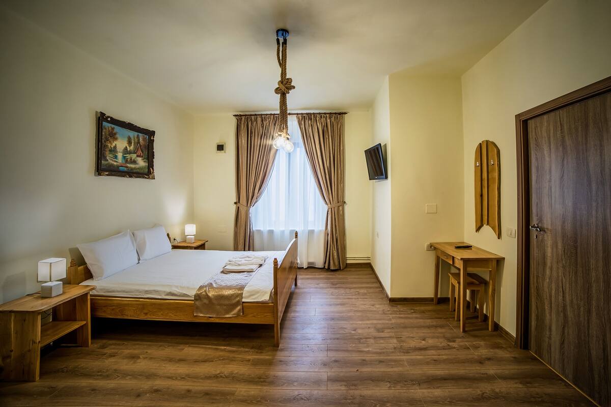 A bedroom with a wooden bed, a nightstand, a desk, and a wardrobe.