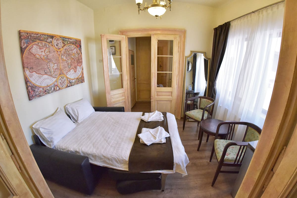 A hotel room with a bed, a desk, a chair, a map on the wall, and a wardrobe.