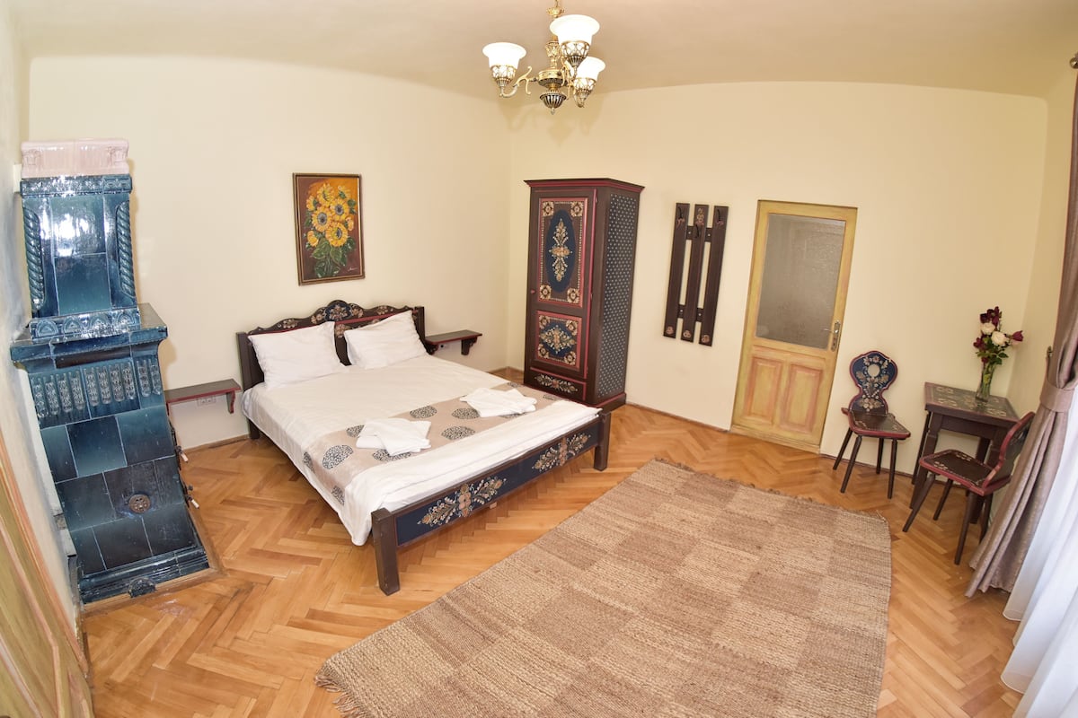 A bedroom with a bed, a dresser, a chair, a rug, and a door.