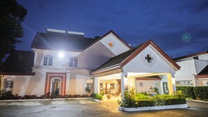 A large, well-lit building with a prominent entrance, a covered porch, and a landscaped garden area. - Villa Ibarra (Tagaytay)