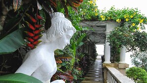A white statue of a woman in a garden setting with a stone pathway and lush greenery. - Villa Ibarra (Tagaytay)