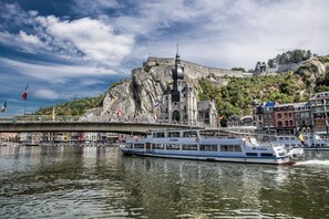 Une rivière sur laquelle navigue un bateau appelé «Le Sex», et en arrière-plan, un bâtiment historique doté d’un clocher.