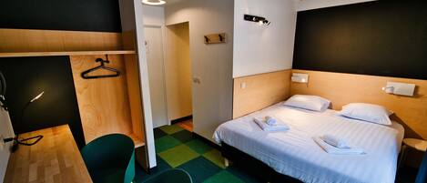 Una camera d'albergo con un letto, una scrivania, una sedia e un armadio.