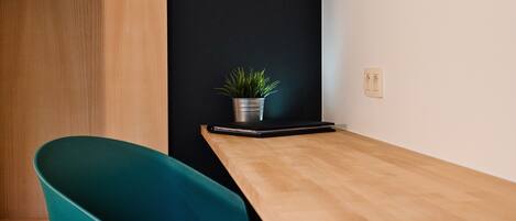 Een vergaderruimte met een houten tafel, een teal stoel en een potplant.