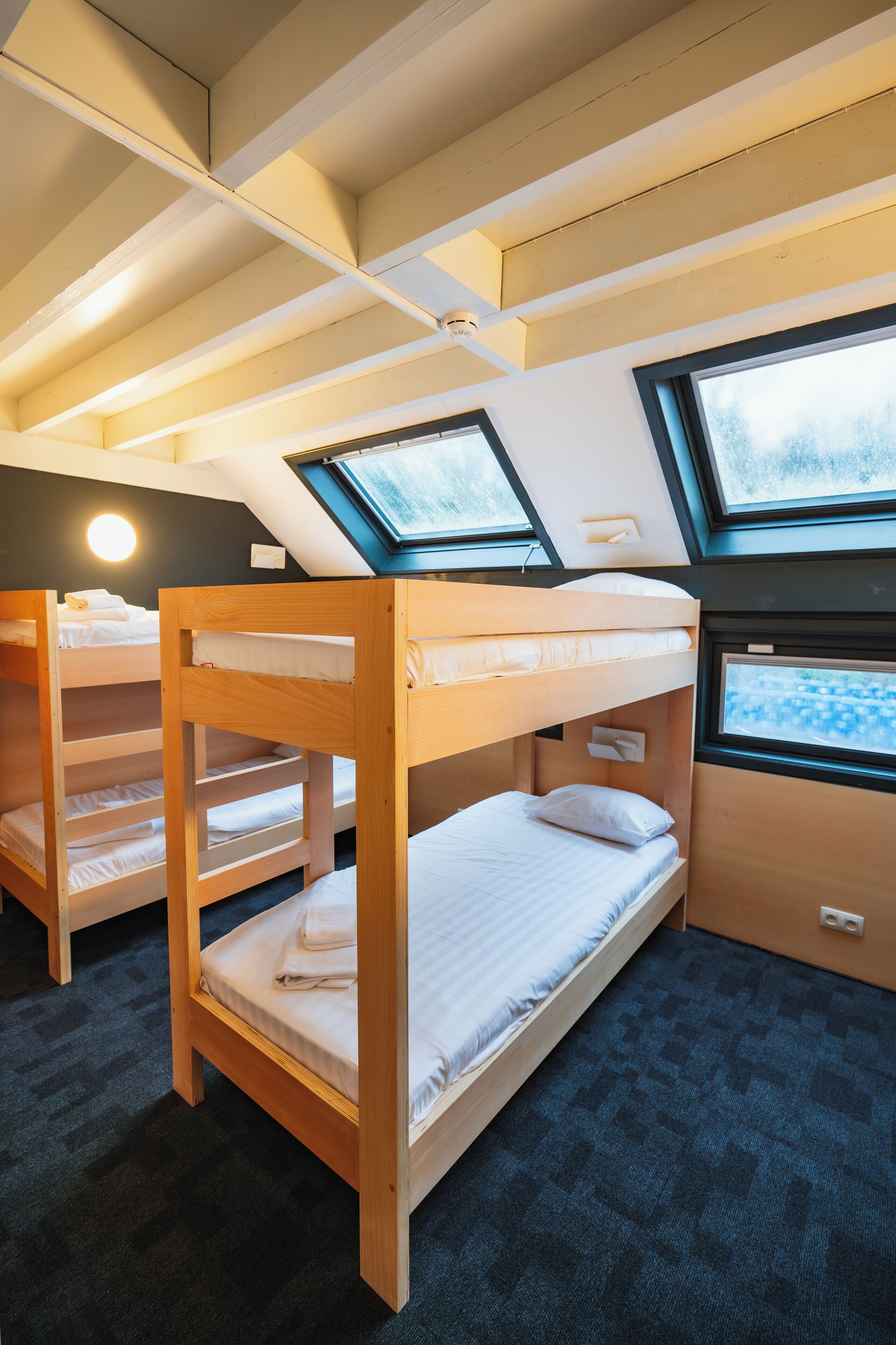A bunk bed room with skylights, a desk, and a window.