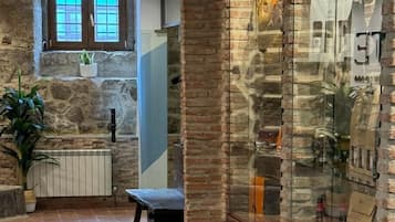 Un pasillo amplio con suelo de baldosas, una pared de piedra y una vitrina de vidrio, además de un banco.
