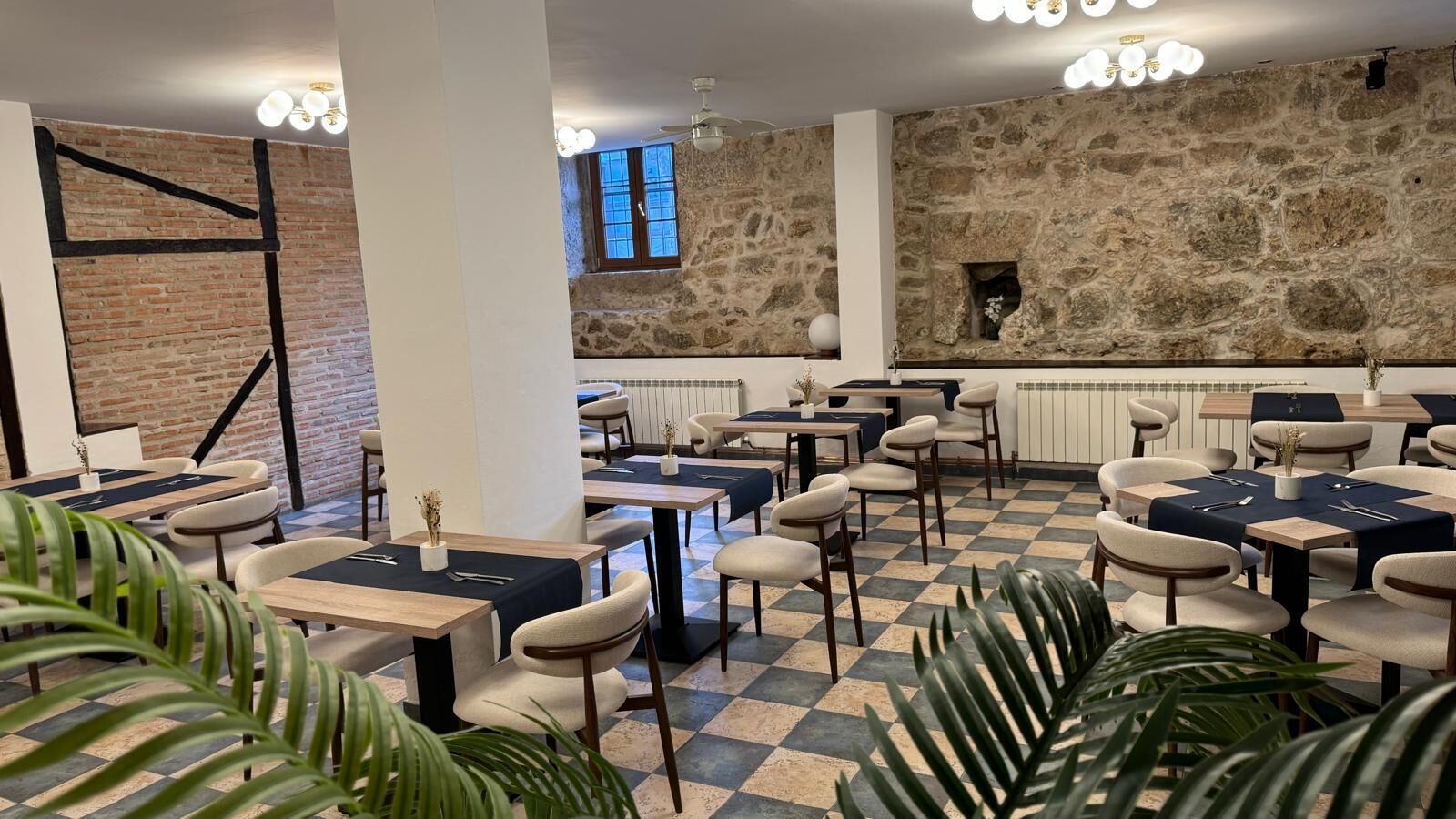 Un restaurante con pared de piedra, suelo a cuadros y varias mesas y sillas.