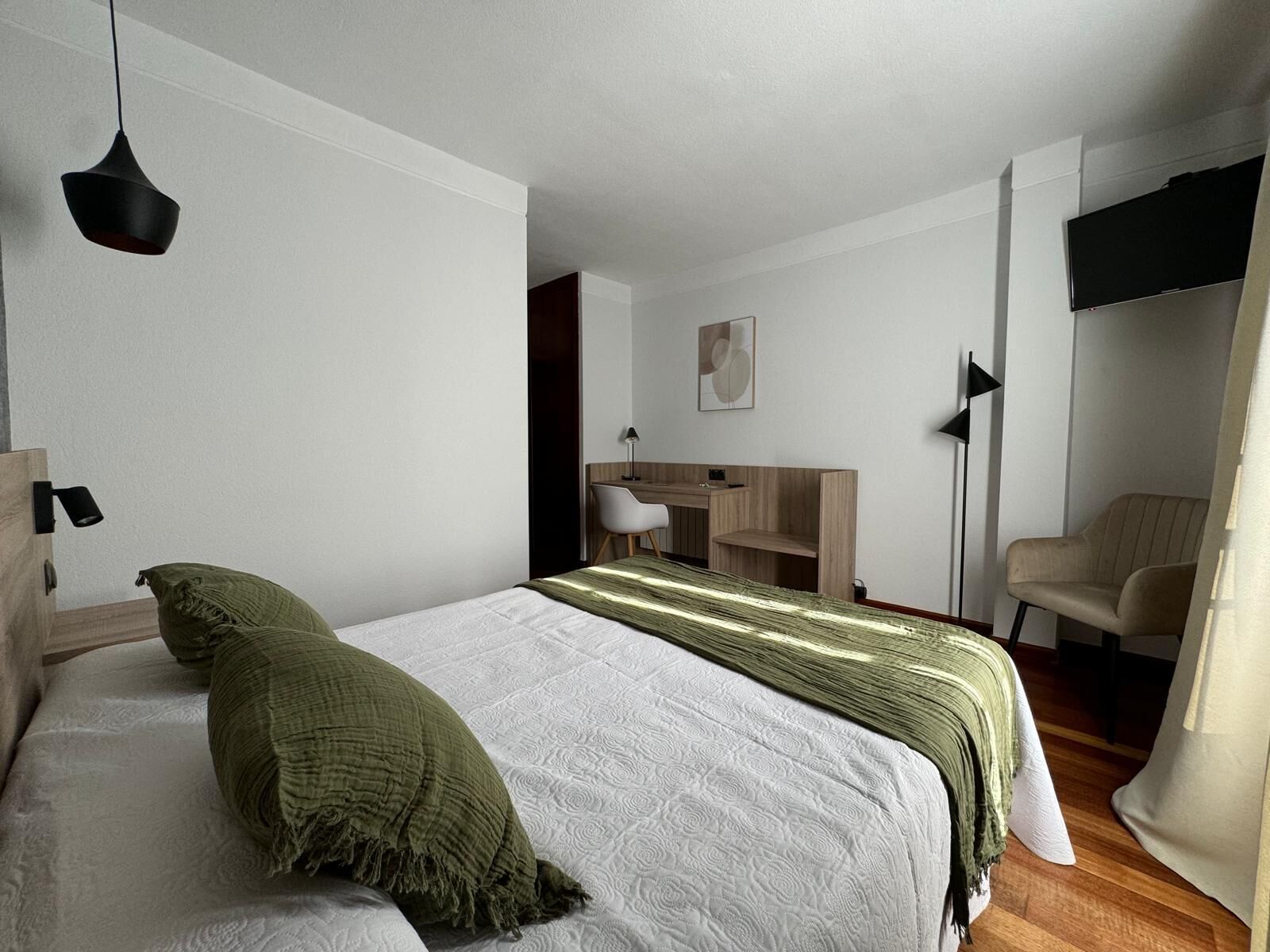 Une chambre à coucher moderne avec un lit, un bureau, une chaise et un téléviseur.