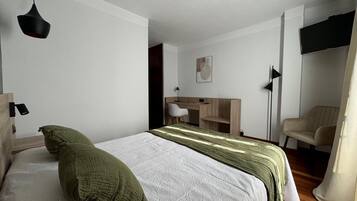 Une chambre à coucher moderne avec un lit, un bureau, une chaise et un téléviseur.