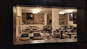 Een restaurant met een stenen muur, verschillende tafels en stoelen, en moderne verlichting.