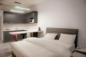 A modern hotel room with a bed, bedside table, and a kitchenette area including a microwave and a coffee maker. - 41 Twelve (Beirut)