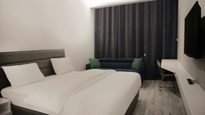 A modern hotel room with a large bed, a small sofa, a TV, and a desk with a chair. - 41 Twelve (Beirut)