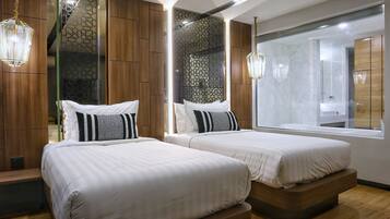 A modern hotel room with two beds, wooden paneling, a large mirror, and a view of the bathroom.