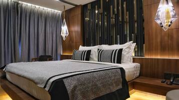 A modern hotel room with a large bed, a wooden headboard, a desk with a chair, and a large window with curtains.
