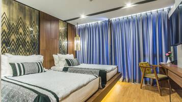 A hotel room with two beds, a desk, and a chair.