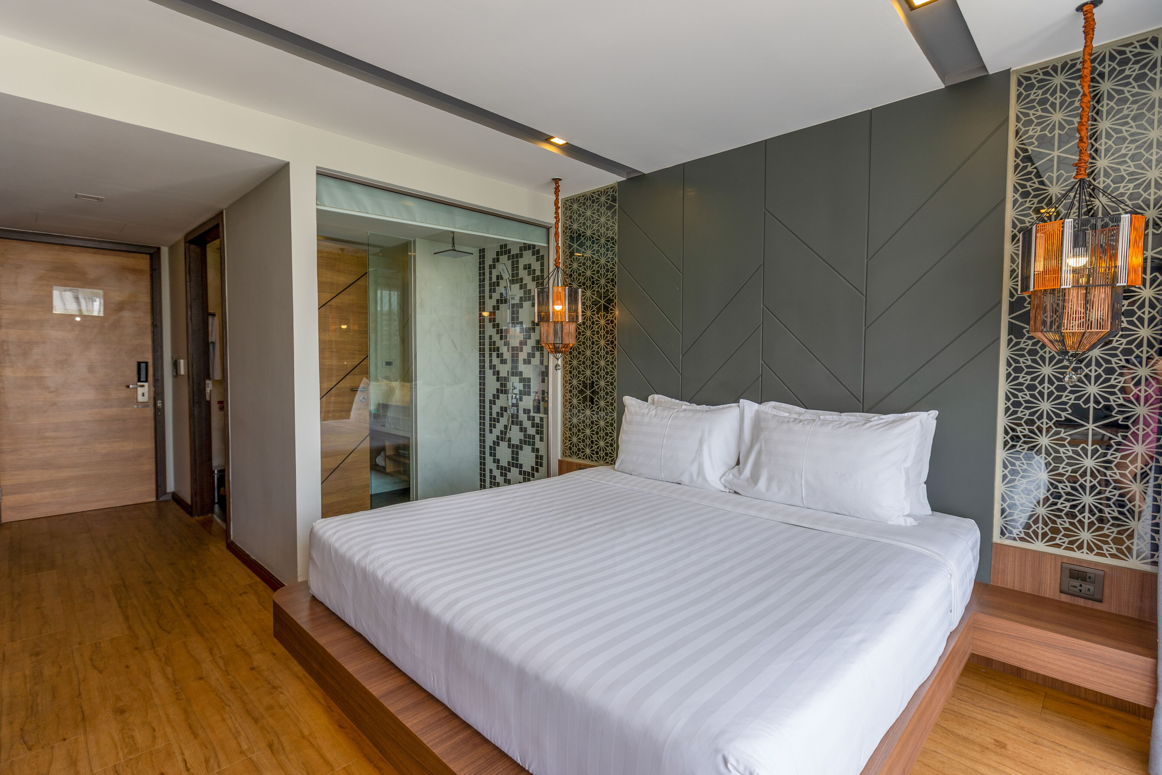 Habitació d'hotel moderna amb un llit gran, un armari encastat i una paret amb un disseny decoratiu.