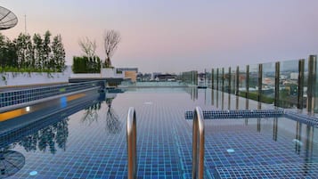 A rooftop infinity pool with glass railings, a clear view of the cityscape, and a modern architectural design.