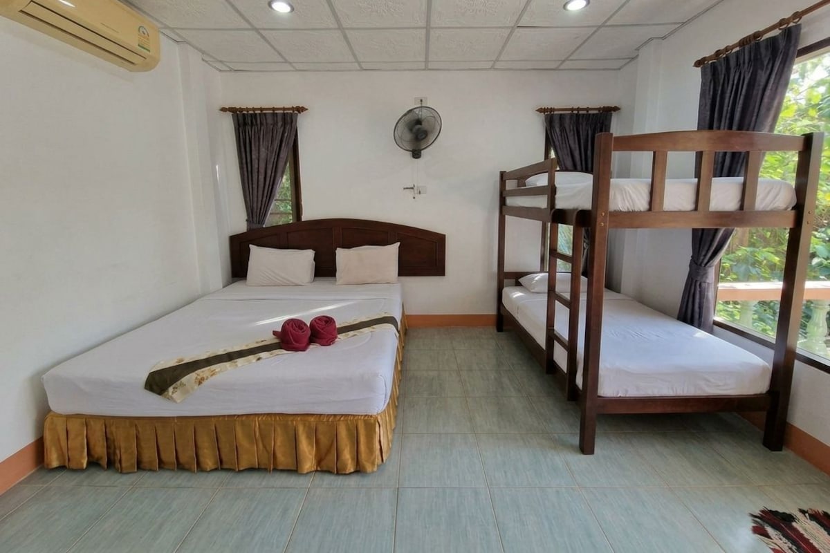 A room with a bunk bed, a single bed, a ceiling fan, and an air conditioning unit.