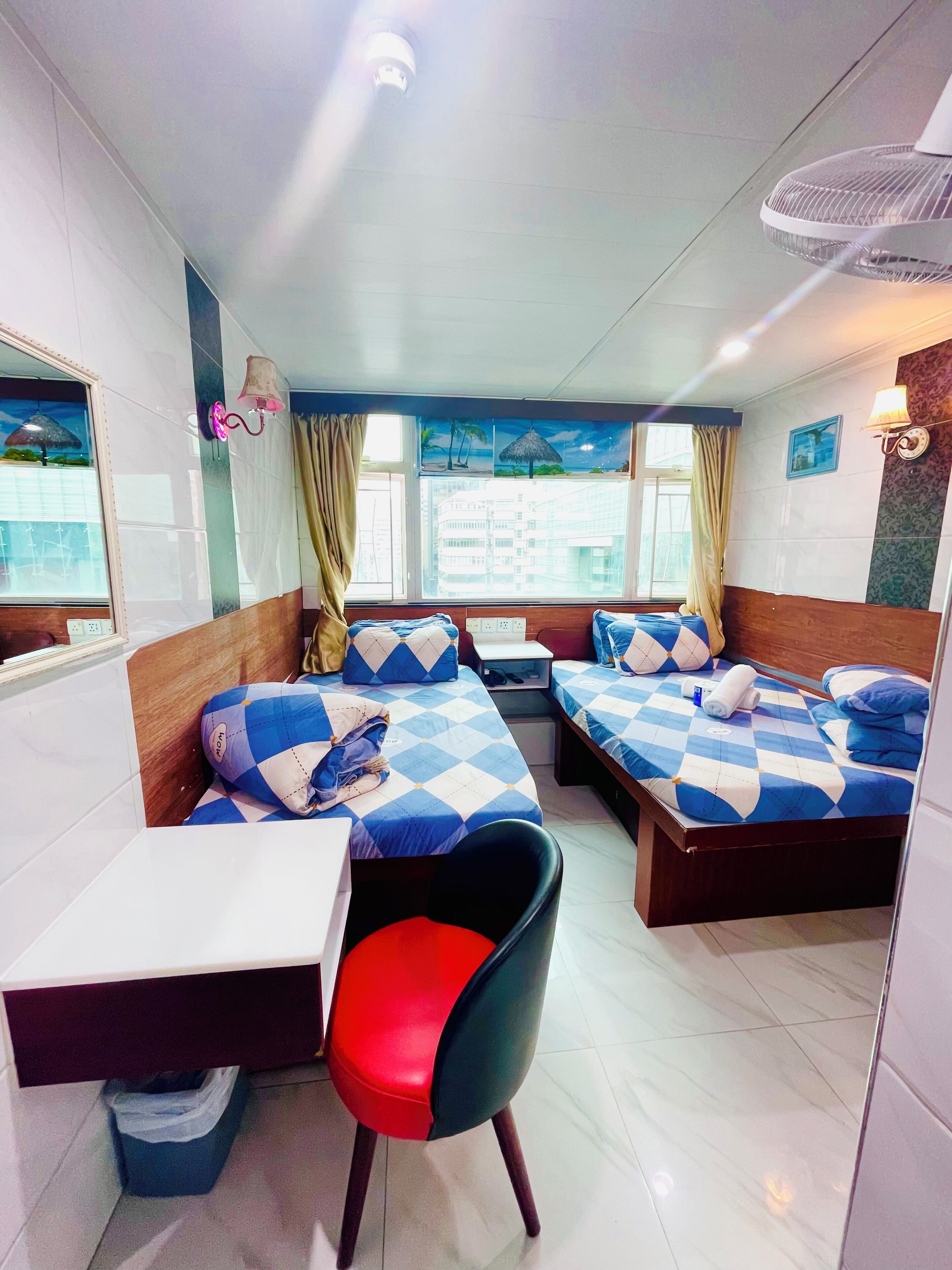 A hotel room with two beds, a desk, and a chair.