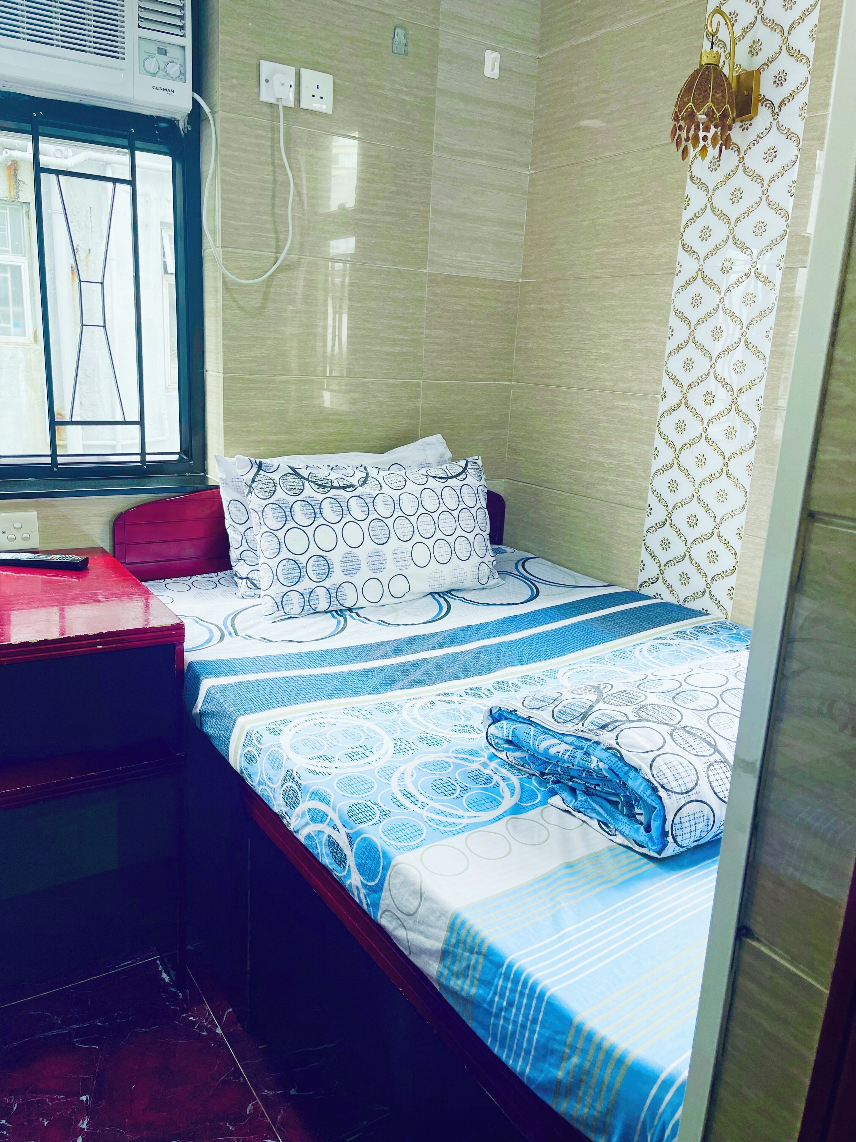 Une chambre d’hôtel de taille réduite, comprenant un lit, un petit bureau et une fenêtre.