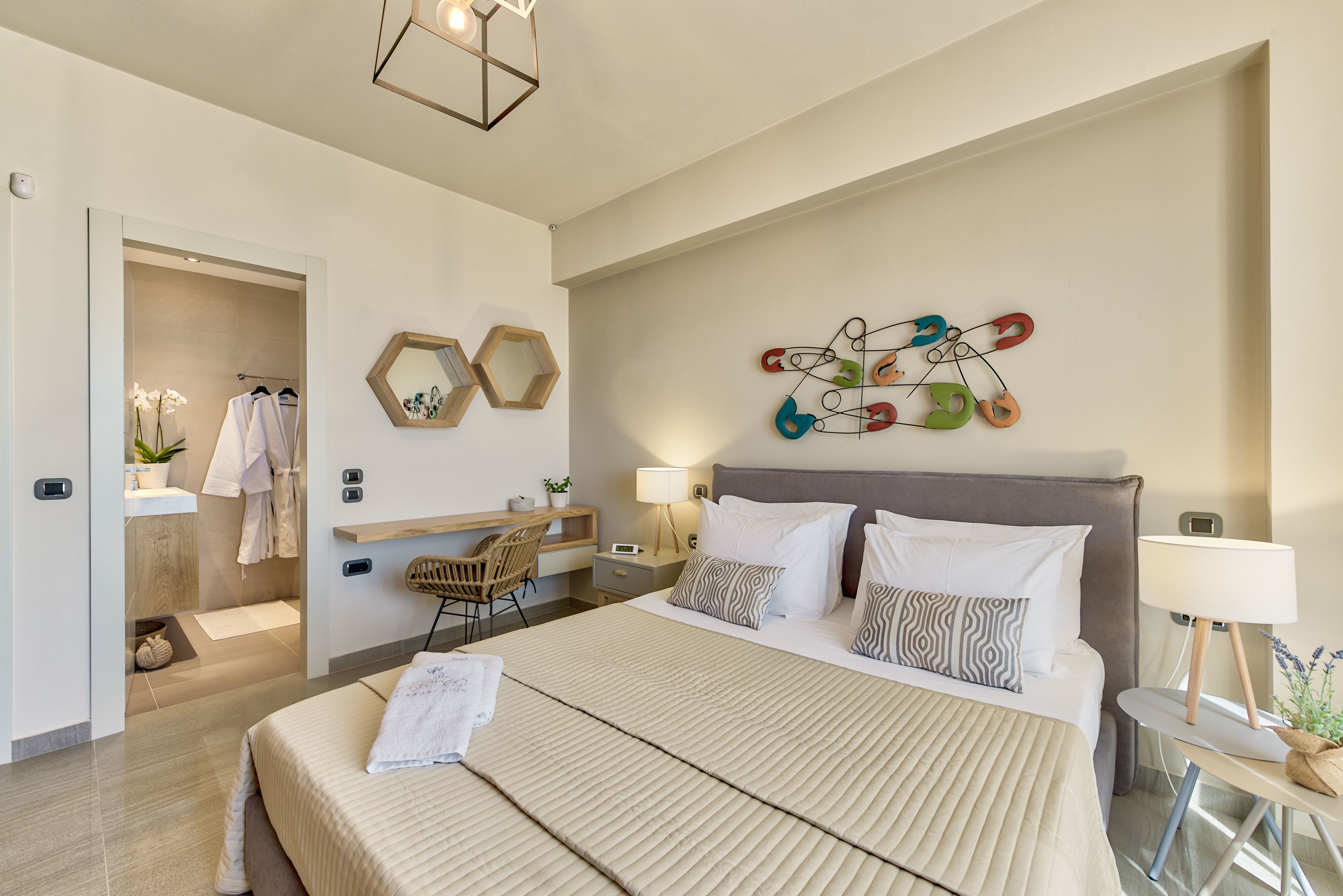 Ett modernt hotellrum med en stor säng, sängbord, ett skrivbord och ett abstrakt konstverk som hänger på väggen.
