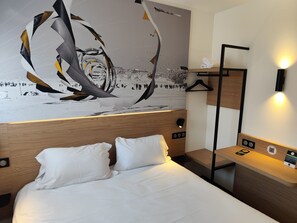A hotel room with a bed, a nightstand, a wall-mounted lamp, and a wall art depicting a snowy landscape. - B&B HOTEL Berck-sur-Mer Rang-du-Fliers (Rang-du-Fliers)