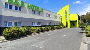 Een bed-and-breakfast hotel met een moderne gevel, meerdere ramen en een parkeerplaats.