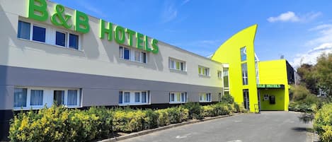 Un hotel B&B con una facciata moderna, diverse finestre e un'area parcheggio.