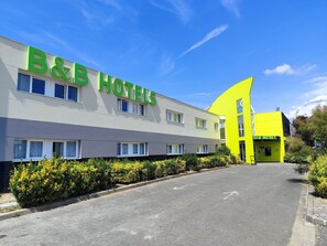 A B&B hotel with a modern facade, multiple windows, and a parking area.