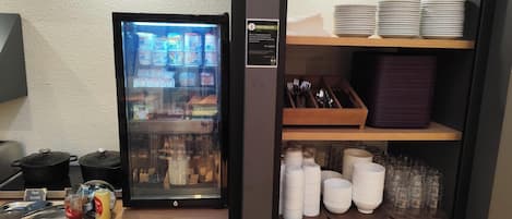 Un espace de petit-déjeuner en libre-service équipé d’un réfrigérateur, de condiments et d’ustensiles.