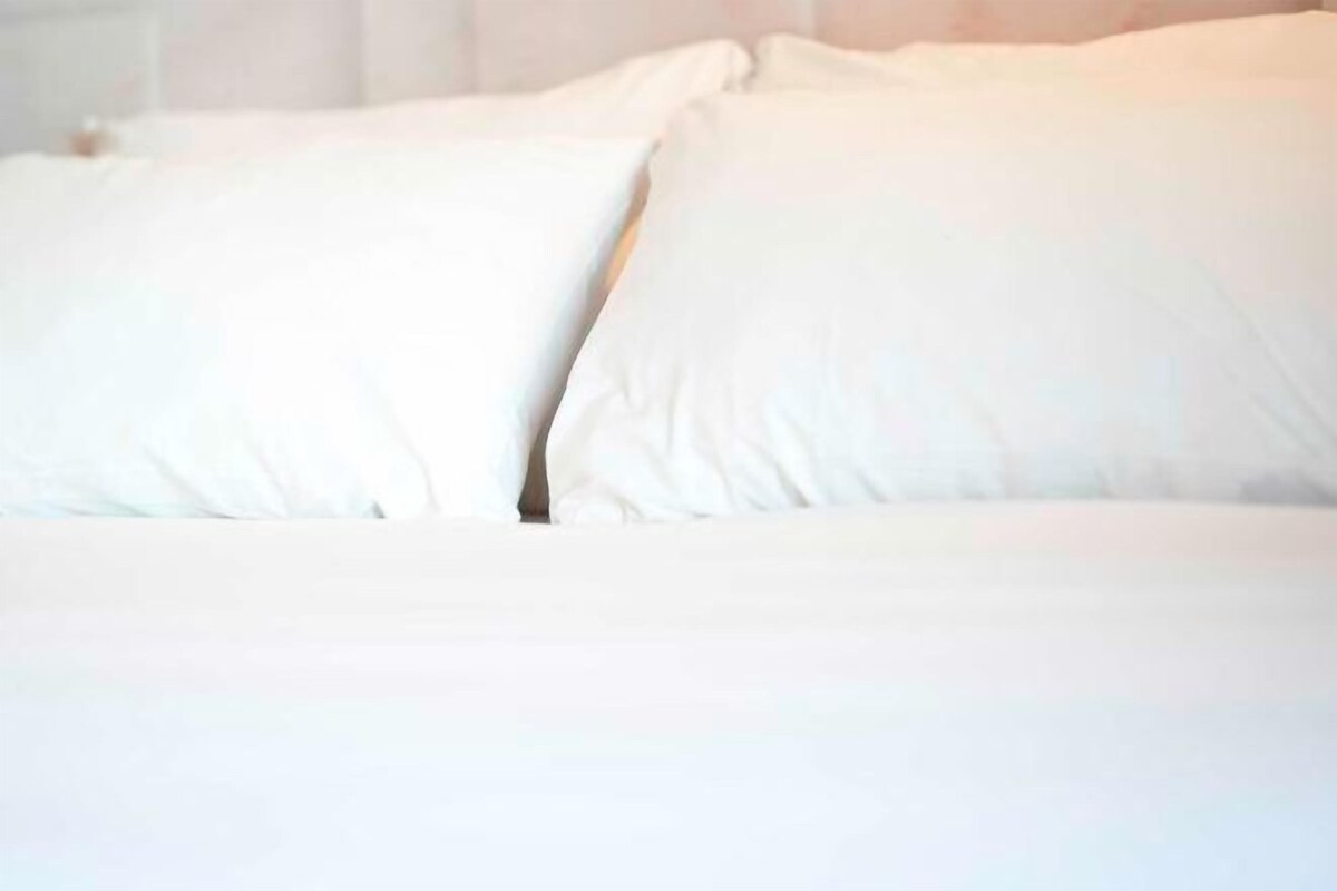 A bed with white bedding and pillows.