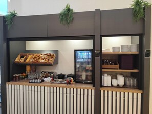 Un comptoir de restauration proposant une variété de produits de boulangerie et un distributeur de boissons.