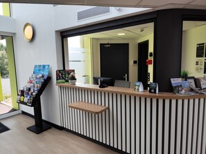 A reception desk with informational brochures, a potted plant, and a computer. - B&B HOTEL Berck-sur-Mer Rang-du-Fliers (Rang-du-Fliers)