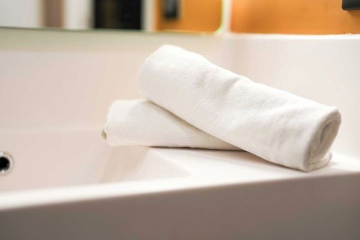 Een witte handdoek gevouwen op een witte wasbak in een badkamer.